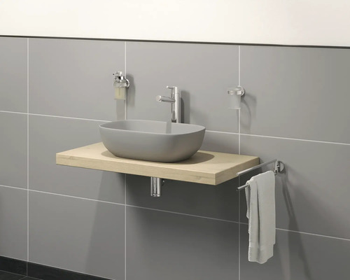 Chiuvetă de baie cu lavoar aplicat, robinet, dispenser de săpun, suport pentru periuțe de dinți și suport pentru prosop în fața unui perete cu gresie