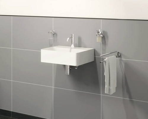 Chiuvetă de perete cu robinet, dozator de săpun, prosop și pahar pentru periuțe de dinți într-o baie