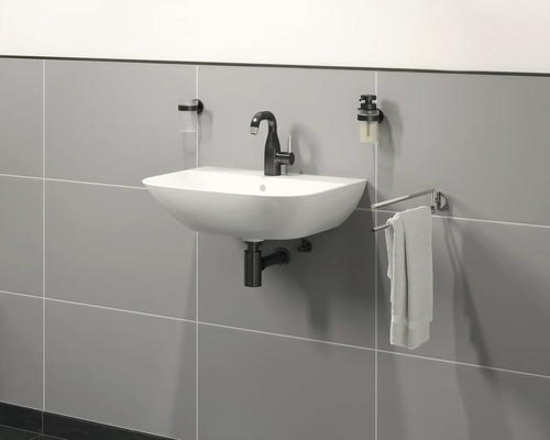 Chiuvetă de perete cu baterie, dozator de săpun și suport pentru prosoape în fața unui perete cu gresie