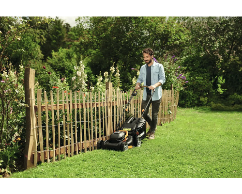 Bărbat tunde gazonul cu o mașină de tuns iarba într-o grădină