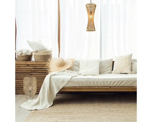 Cameră de zi cu canapea, perne, pături, coșuri, lampă și covor