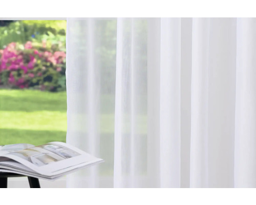 Perdea albă transparentă în fața unei ferestre cu vedere la grădină