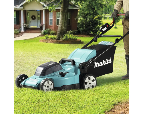 Mașină de tuns iarba marca Makita utilizată pe un gazon din fața unei case.