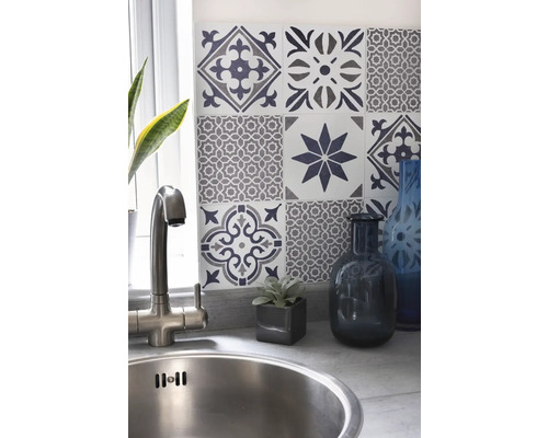 Chiuvetă cu baterie în fața unui perete cu plăci decorative într-o zonă de bucătărie.