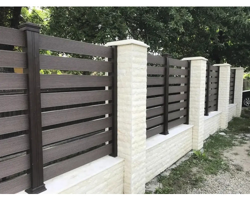 Vedere spre grădină cu gard din lamele de plastic și stâlpi de piatră