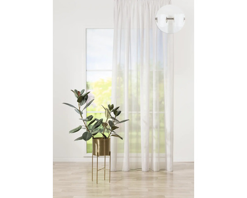 Perdea albă cu ochiuri în fața unei ferestre, cu o plantă de apartament într-un ghiveci.