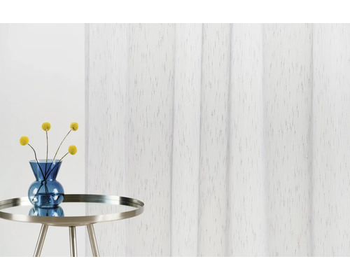 Panou decorativ din material textil lângă o masă cu flori într-o vază