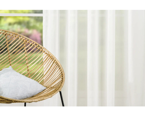 Living decorativ cu fotoliu din ratan și perdea transparentă