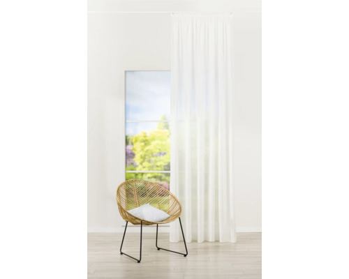 Cameră luminoasă cu scaun de ratan, pernă și perdea albă