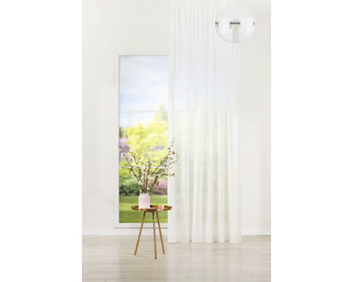 Perdea albă cu ochiuri în fața unei ferestre cu vedere spre grădină