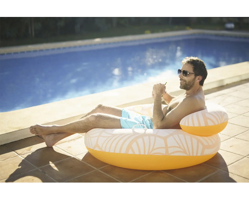 Bărbat relaxându-se pe un scaun gonflabil la piscină, lângă piscină