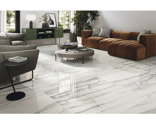 Living luminos cu gresie albă cu aspect de marmură, canapea și măsuță laterală.