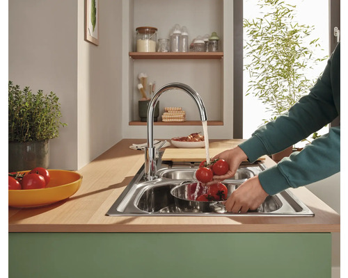 Chiuvetă din oțel inoxidabil cu o persoană care spală roșii sub jet de apă