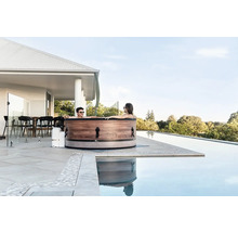 Cuplu relaxându-se într-o cadă cu hidromasaj pe o terasă lângă o piscină.
