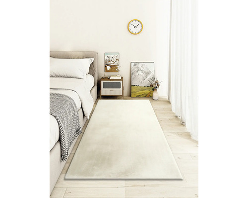 Dormitor luminos cu pat, noptieră și covor lung, dreptunghiular