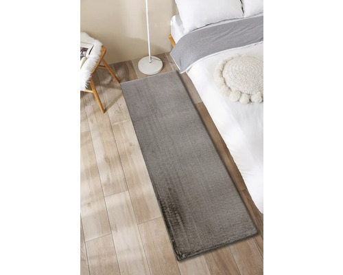 Covor gri lângă un pat pe o podea de lemn