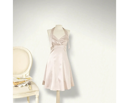 Rochie pe manechin lângă un scaun cu accesorii de cusut