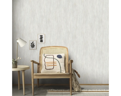 Scenă cu scaun de ratan, masă, lampă și tapet cu model în fundal.