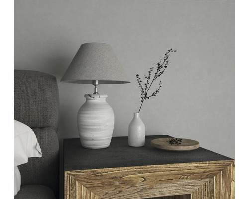 Lampă de masă decorativă cu abajur lângă o vază cu o creangă pe o noptieră