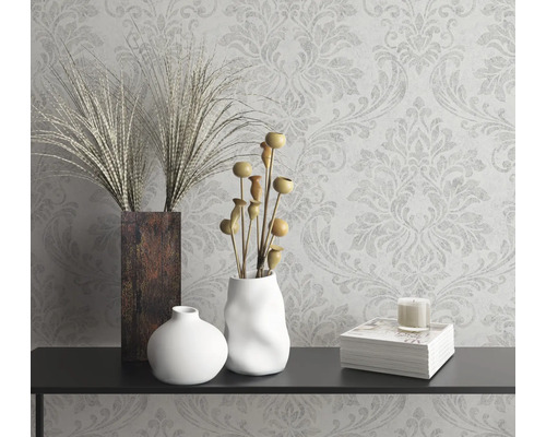 Natură statică decorativă cu vaze, plante ornamentale, lumânare și carte pe o consolă în fața unui tapet cu model