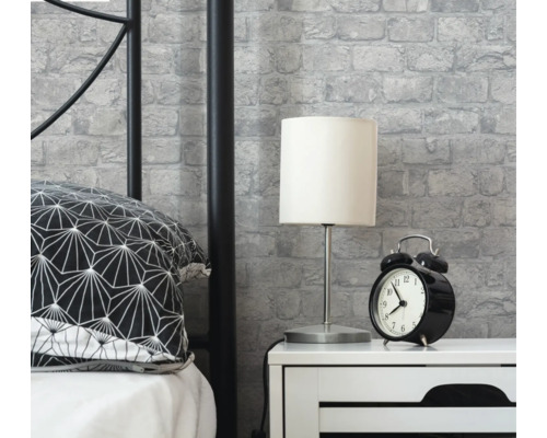 Scenă de dormitor cu pat, noptieră, lampă, ceas deșteptător și tapet cu zidărie