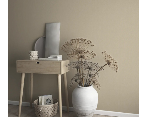 Aranjament decorativ cu măsuță laterală, vază cu flori uscate și elemente decorative în fața unui perete uni.