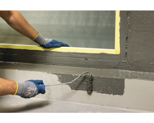 Aplicarea mortarului de etanșare cu o rolă de vopsea pe un pervaz.