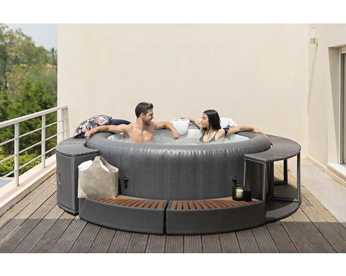 Jacuzzi gonflabil cu doi oameni și o zonă de relaxare în jur pe o terasă.