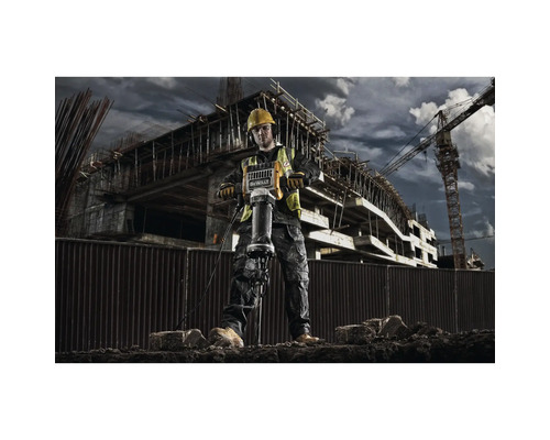 Un muncitor în construcții operează un ciocan pneumatic pe un șantier.