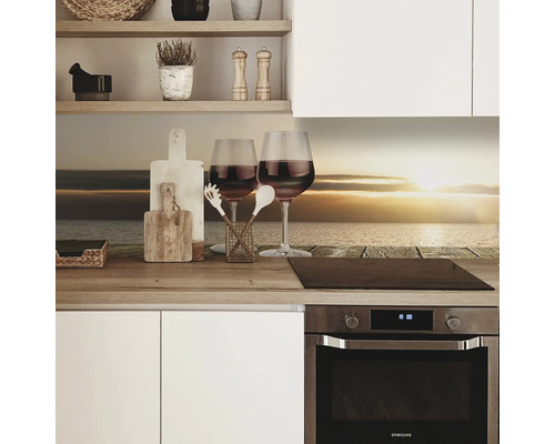 Scenă de bucătărie cu un panou de protecție împotriva stropilor, două pahare de vin și ustensile de bucătărie pe un blat de lucru