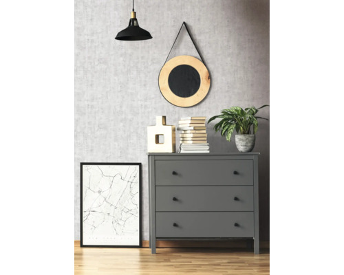 Comodă gri cu trei sertare într-o cameră cu elemente decorative, cum ar fi o lampă, o oglindă și o imagine înrămată.