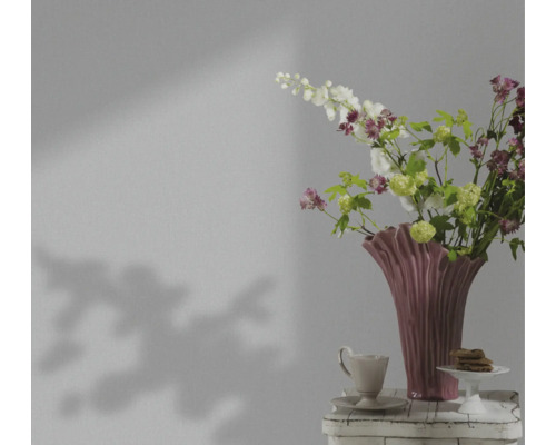 Natură statică decorativă cu flori într-o vază, ceașcă și produse de patiserie pe o masă