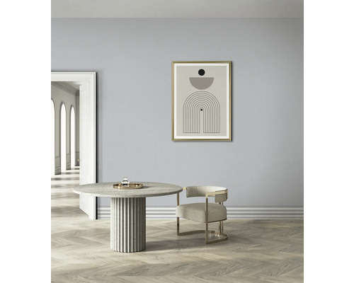 Interior luminos cu o masă rotundă, un scaun și o reproducere artistică înrămată pe perete