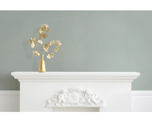 Crenguțe decorative aurii de ginkgo într-o vază pe șemineu alb