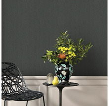 Living decorativ cu tapet negru cu aspect de lemn, o măsuță laterală cu o vază de flori și un scaun de design.