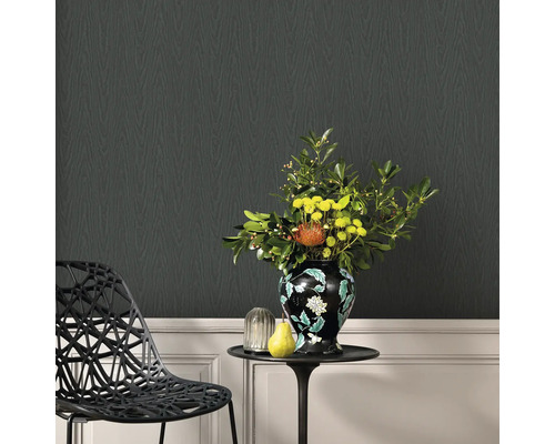 Living decorativ cu tapet negru cu aspect de lemn, o măsuță laterală cu o vază de flori și un scaun de design.