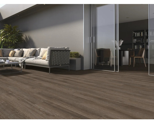 Terasa cu podea din lemn închis la culoare, canapea și vedere spre o cameră cu bibliotecă