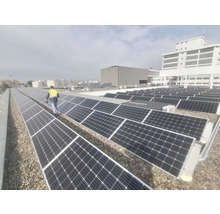 Fotografie cu panouri solare pe un acoperiș cu o persoană care poartă o vestă de siguranță