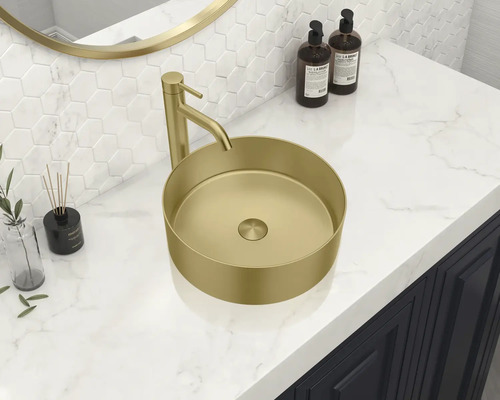 Pe o chiuvetă se află o chiuvetă așezată pe blat de culoare aurie cu robinet