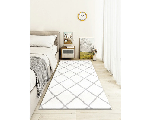 Dormitor cu pat, noptieră și covor alb cu model în romburi