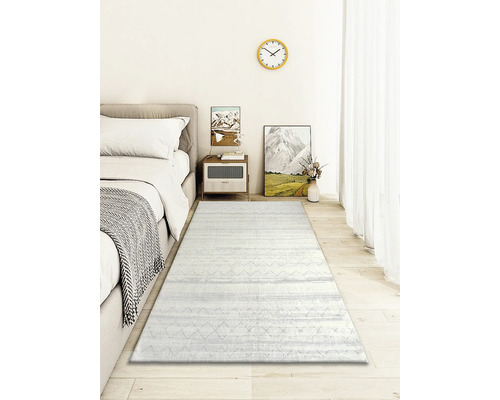 Dormitor cu pat, noptieră, decorațiuni și un covor deschis la culoare cu model.