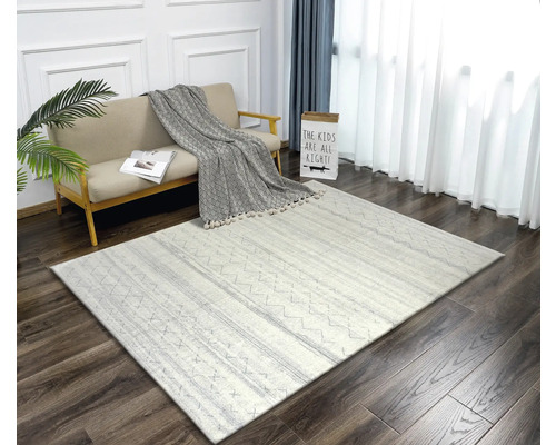 Living cu canapea, pernă decorativă și covor cu model pe podea de lemn.