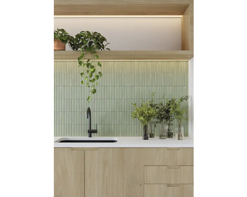 Scenă de bucătărie cu chiuvetă, robinet, blat, fundal cu gresie verde și plante de apartament