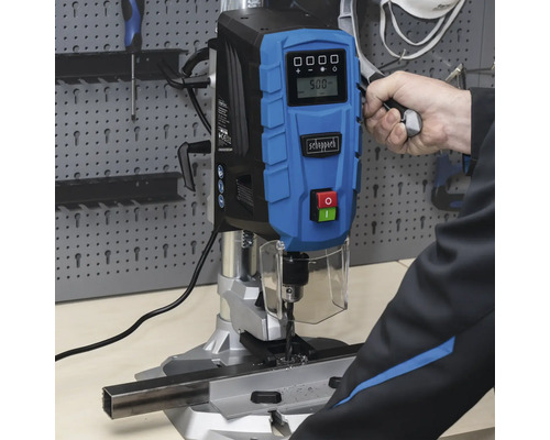 Mașină de găurit cu coloană Scheppach care găurește o bucată de metal.