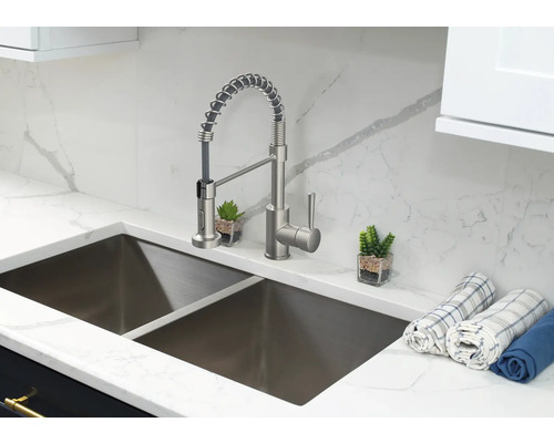 Chiuvetă de bucătărie din oțel inoxidabil cu robinet și cârpe de vase pe un blat de marmură.