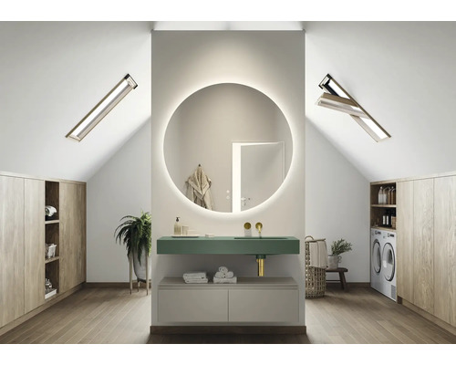 Baie modernă la mansardă cu oglindă rotundă, lavoar, mașină de spălat și dulapuri din lemn