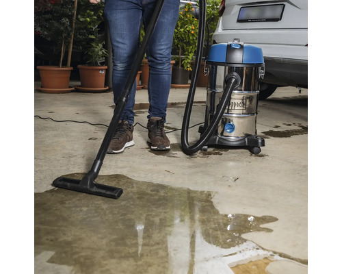 O persoană folosește un aspirator umed-uscat Scheppach pentru a aspira apa.