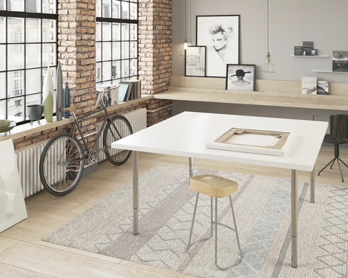 Cameră luminoasă cu fereastră mare, perete de cărămidă, masă albă, taburet și bicicletă