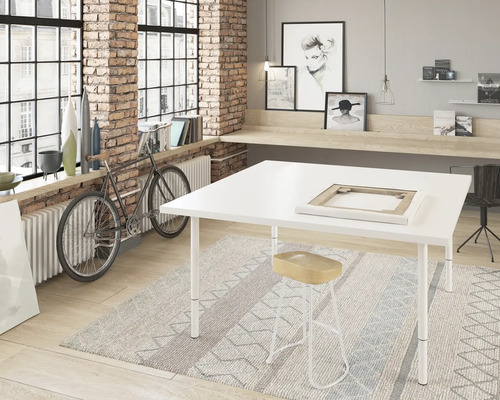 Cameră luminoasă cu fereastră mare, masă de atelier, taburet și decorațiuni.