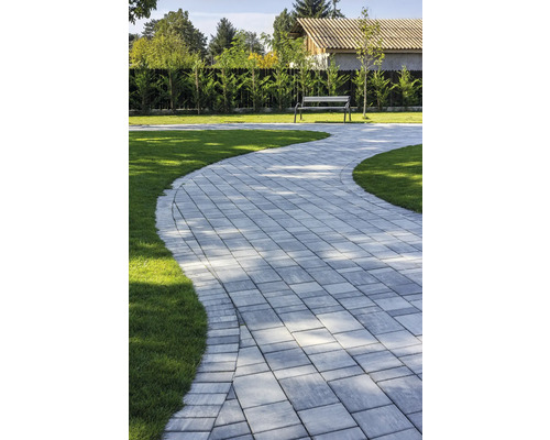 Alei de grădină din pavaj, gazon și bancă în fundal